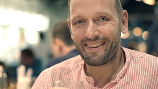 Happy man drinking beer in cafe at night

