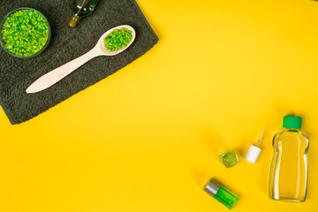 Spa set: soap, mask, oil, sea salt and towel on yellow background