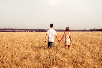 love couple walking in sunset field holding hands