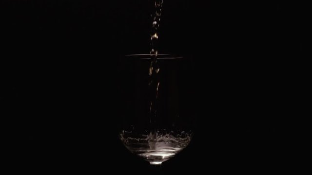 Slow mo bursts of white wine in glass