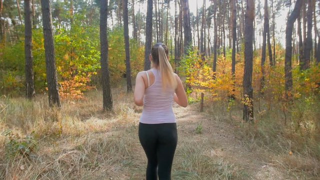 Slow motion of young woman running in pine forest at morning