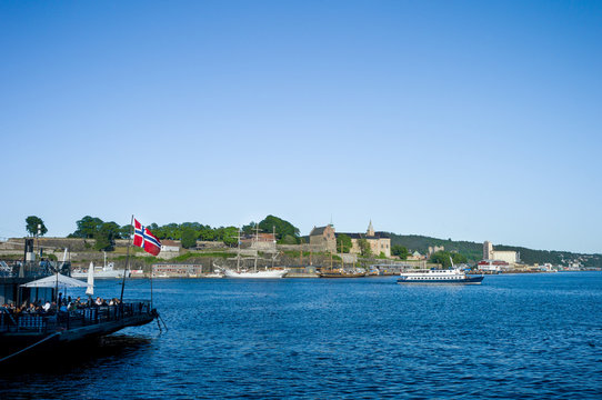 Oslo harbour. Aker Brygge. Boats near Akershus Castle. Norwegian flag