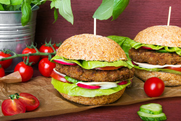 Homemade hamburgers with fresh vegetables on wooden background