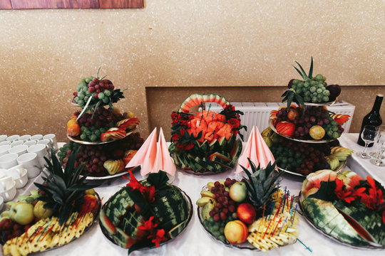 Different kinds of fruits served on tired dishes