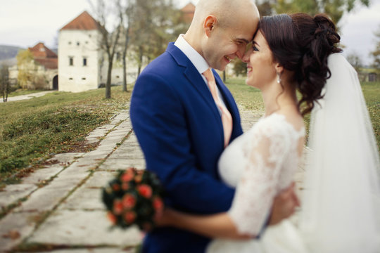 Blurred picture of happy newlyweds hugging before old castle