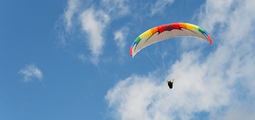 Paragliding flight with blue sky and some clouds