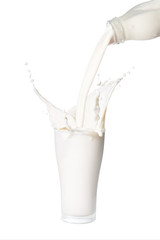 Pouring milk from bottle into glass with splashing., Isolated white background.