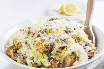 Caesar Salad with on white plate. Delicious Caeser salad with croutons, roasted chicken meat, parmesan cheese and cos lettuce, with sauce, healthy recipe, close-up. Healthy food.