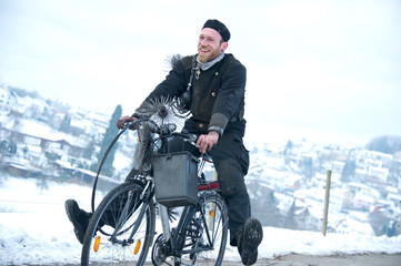 Schornsteinfeger fährt in lustiger Haltung mit Fahrrad im Winter