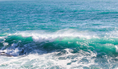 Beautiful sea waves splash with white foam on a blue ocean surface background.