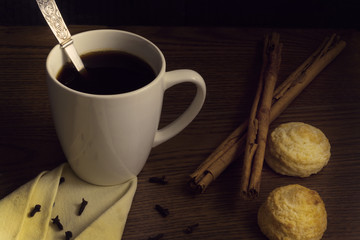 Cup coffee with cinnamon and cookies on wooden table