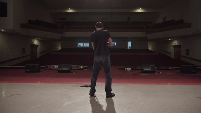 Man washes theater stage using a mop