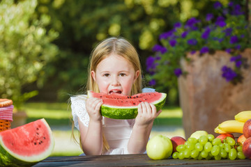 Happy girl with big red slice of watermelon sitting on rustic ta © Jarek Pawlak