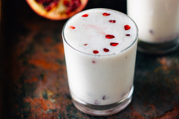Traditional indian drink - lassi - cold yougurt dessert with the pomegranate seeds.