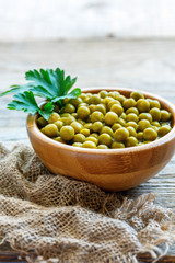 Wooden bowl with canned green peas.