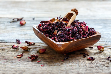 Petals of hibiscus tea in a wooden bowl. - obrazy, fototapety, plakaty