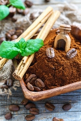 Ground coffee and cinnamon sticks in a wooden bowl.