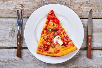 Cutlery near plate with pizza.