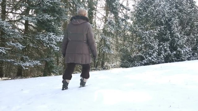 older woman walking in deep snow outdoors
