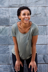 cool young black woman smiling with t-shirt against gray wall