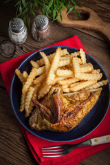 Roasted chicken with french fries on a plate.