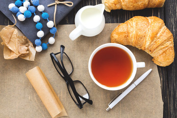 French croissant, glasses, tea and notebook. Workplace concept