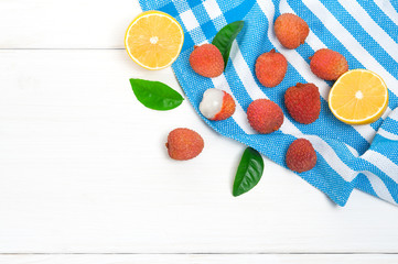 Top view: lychee fruits and lemon half on white wooden bakcground