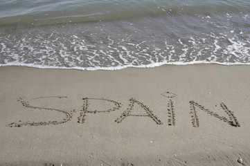 Spain  written in the sand at the beach.