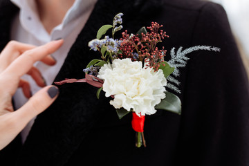 the bride corrects the groom's buttonhole