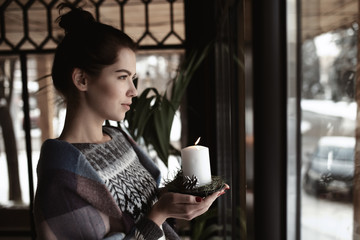 Art photo - woman holding burning candle at window in cafe