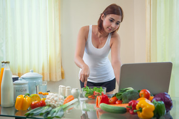 Young asian woman looking for a recipe on the internet in kitche