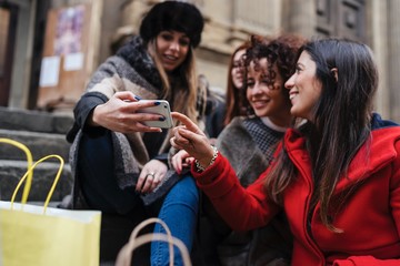Happy female group of friends doing shopping together