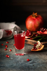 Glass of pomegranate juice. fruits with grains and leaves on the table. Make . Dark moody.