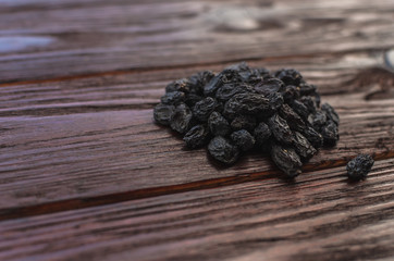 Dark dried grapes (raisins) on a texture wooden table
