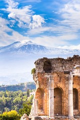Ruins and columns of antique greek theater in Taormina and Etna Mount in the background. Sicily, Italy, Europe. - obrazy, fototapety, plakaty
