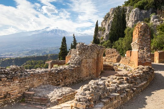 View of ruins of greet antique theatre in Taormina and Etna Mount on a background, Sicily, Europe.