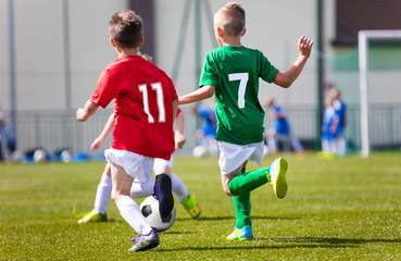 Obraz premium Little boys playing football soccer game on sports field. Football tournament for kids