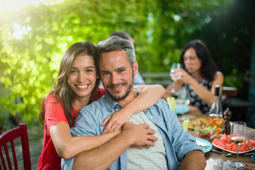 portrait of a couple, they sit with friends around a table
