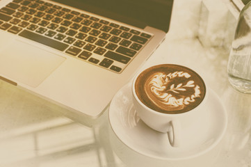 a cup of coffee and laptop on wood floor with flower, vintage st