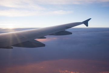 Fototapeta na wymiar View of airplane wing above beautiful cloud at sunbeam and sunse