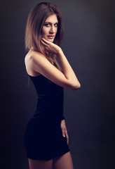 Sexy figure slim model posing in black dress on dark grey backgr