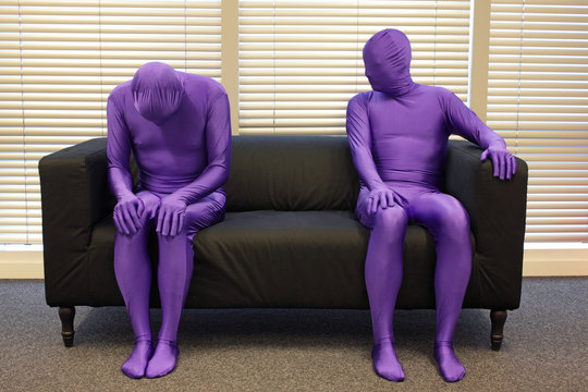 depression.anonymous men  sitting on sofa in office, one is crooked,depressed, another is observing him.