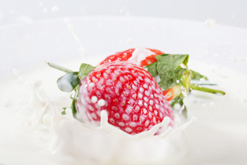 Strawberries falling into fresh bowl of cream