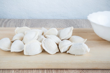 Fototapeta na wymiar Frozen homemade dumplings on the wooden board in the kitchen. Healthy eating.