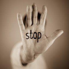 man showing  the word "stop" written on the palm of a his hand