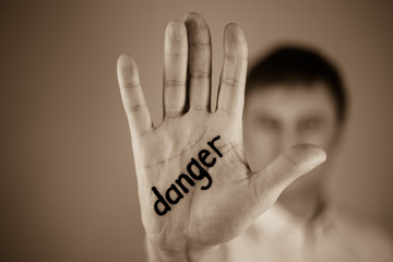 man showing  the word "danger" written on the palm of a his hand