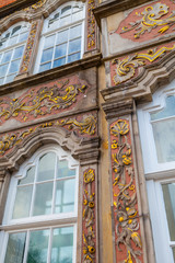 Fototapeta premium Old house facade with windows decorated with painting and gold monograms. German style.