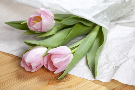 Anniversary pink tulip bouquet wrapped in white paper. Top view at bunch of fresh tulips, image concept for wedding blog, mothers day gift, valentines love card or background