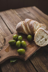 Green olives, sliced ciabatta, feta cheese on a wooden board. Spice. Garlic. Chees Feta. Ciabatta. Olives on a wooden background