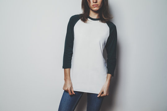 Pretty young girl wearing blank white t-shirt with green long sleeve, empty area for your logo or design, white wall in the background, mock-up of template t-shirt long sleeve